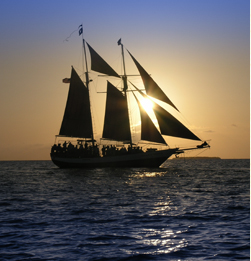 Photo of a gorgeous sunset with a sailboat sailing in front of a setting sun.